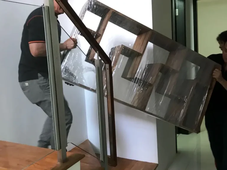 Elite Movers team carefully manoeuvring a wooden sheld up the stairs