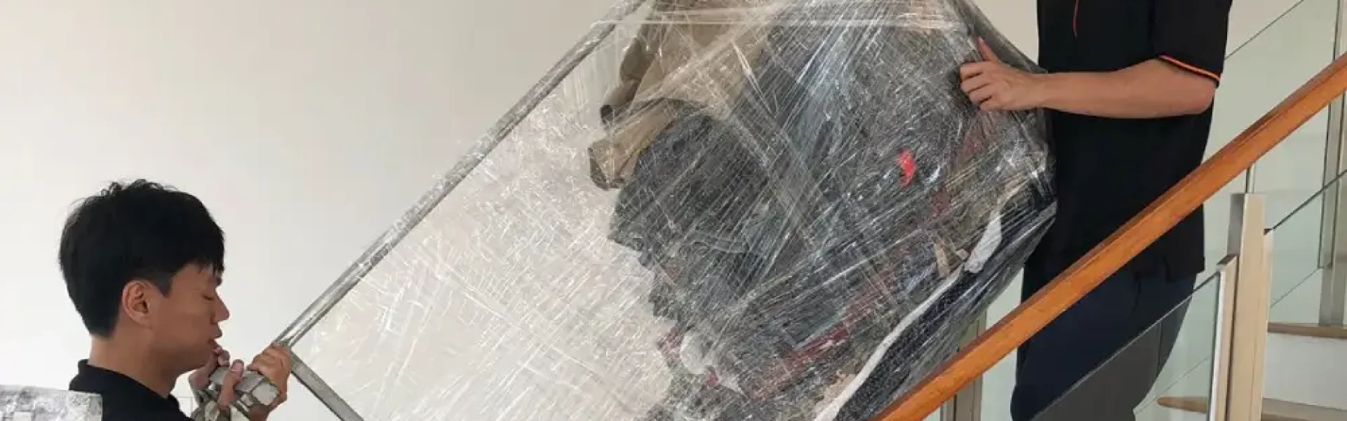 Elite Movers team moving a cling wrapped clothes rack down the stairs